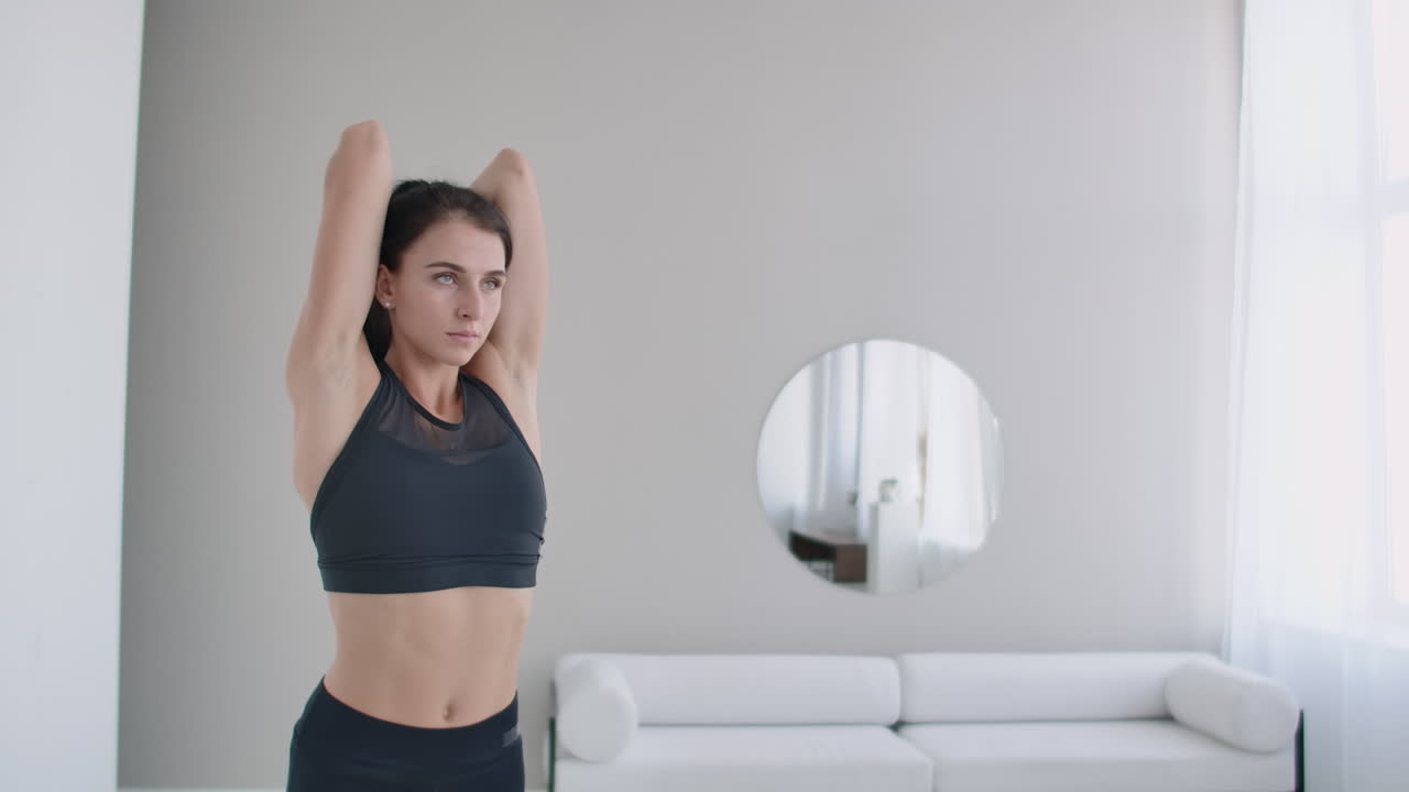 어린 소녀가 머리 뒤에서 덤벨로 팔을 들어 올려 트라이셉스 운동을 한다.