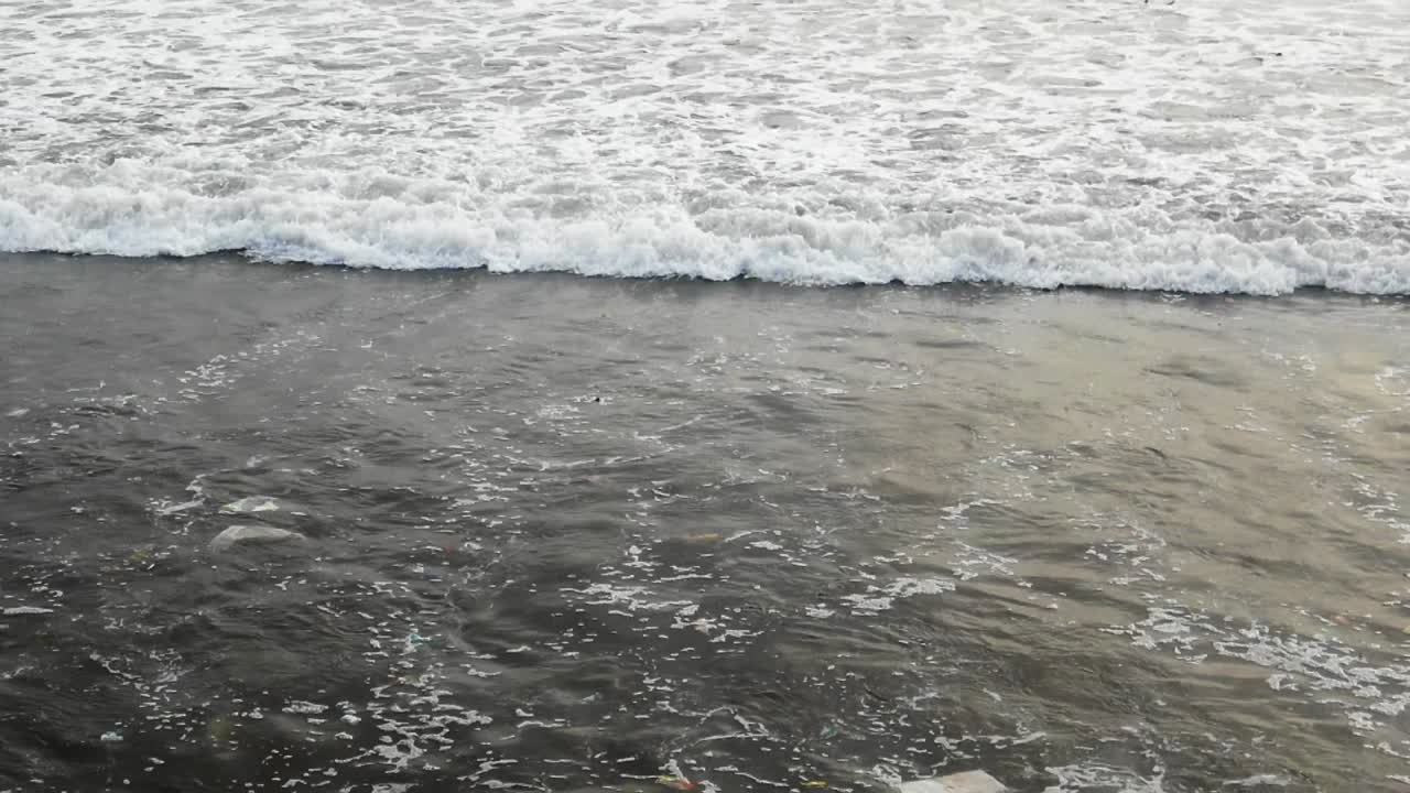 clips en cámara lenta como olas oceánicas sucias y contaminadas golpeando la costa en cámara lenta