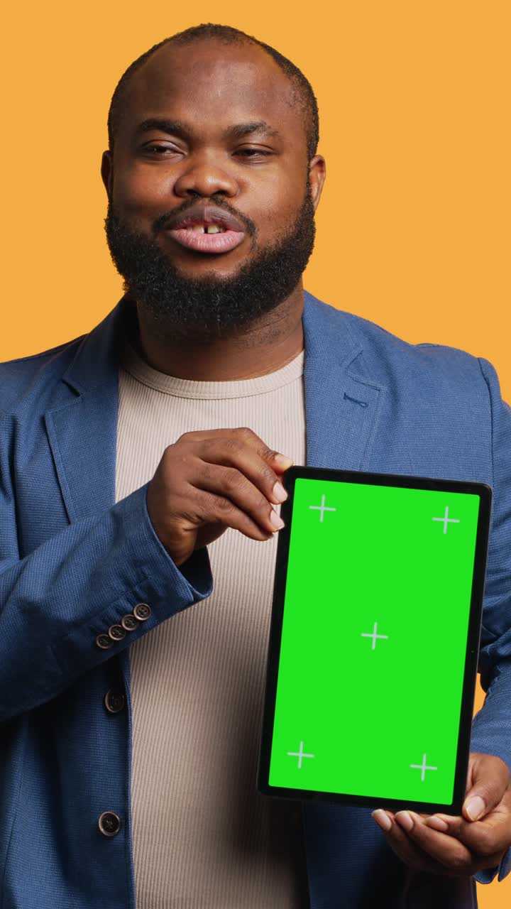 Video verticale ritratto di un uomo che fa influencer marketing usando un tablet con green screen