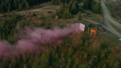 Vista-Aérea-Del-Equipo-De-Filmación-De-Películas-De-Montaña-Con-Pantalla-De-Humo-árboles-Verdes-Creciendo