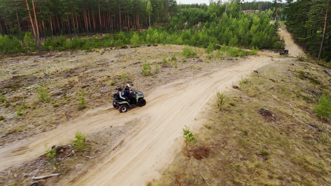 Zooming shot shows adventurous couple riding ATV across sandy Nordic countryside