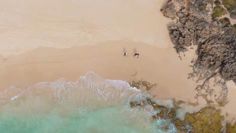 Couple-walking-along-the-Cape-to-Cape-hiking-trail-in-Yallingup,-Western-Australia-through-rocky-beach-section