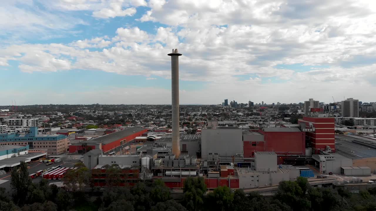 drone volando más allá del bosque revelando las fábricas de la ciudad de melbourne
