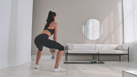 young fitness woman doing squat with dumbbells in hands.