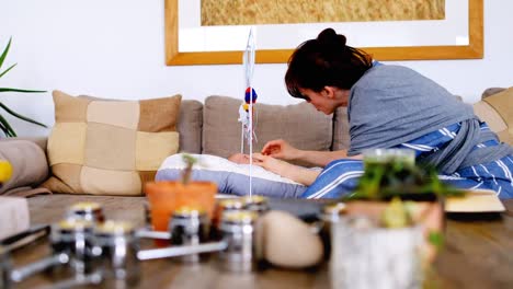 young woman putting her baby in crib to sleep on sofa 4k