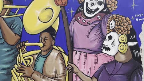 camera tilts down over colorful mural depicting day of the dead skulls and musicians on blue background