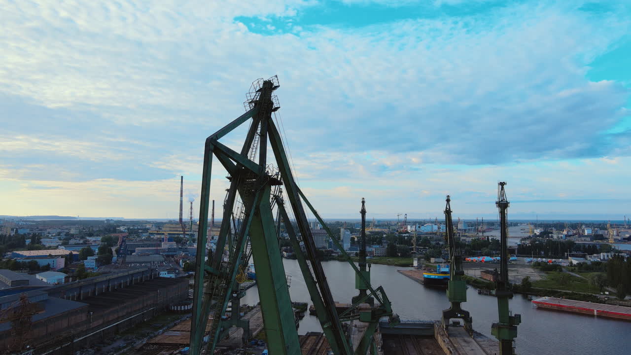 Aerial tilt down shot of industrial cranes at shipyard port of Gdansk in summer