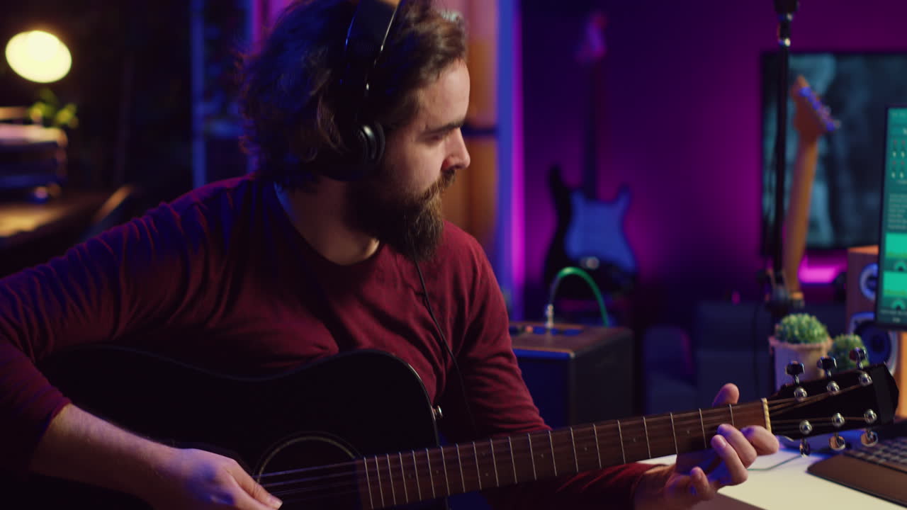 ingeniero de sonido tocando guitarra acústica y usando la consola de mezcla para grabar música