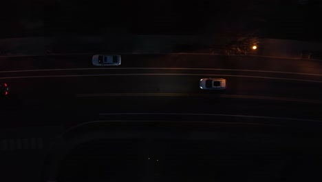 top down aerial tracking of cars driving on street at night