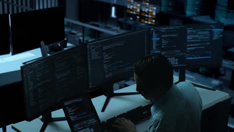 side view of asian man developer working with tablet while write code with multiple computer screens in the office