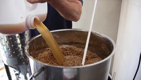 Slow-motion-shot-of-man-pouring-liquid-into-fermenter-to-make-beer