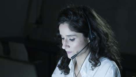joven mujer de negocios con auriculares trabajando en una oficina oscura