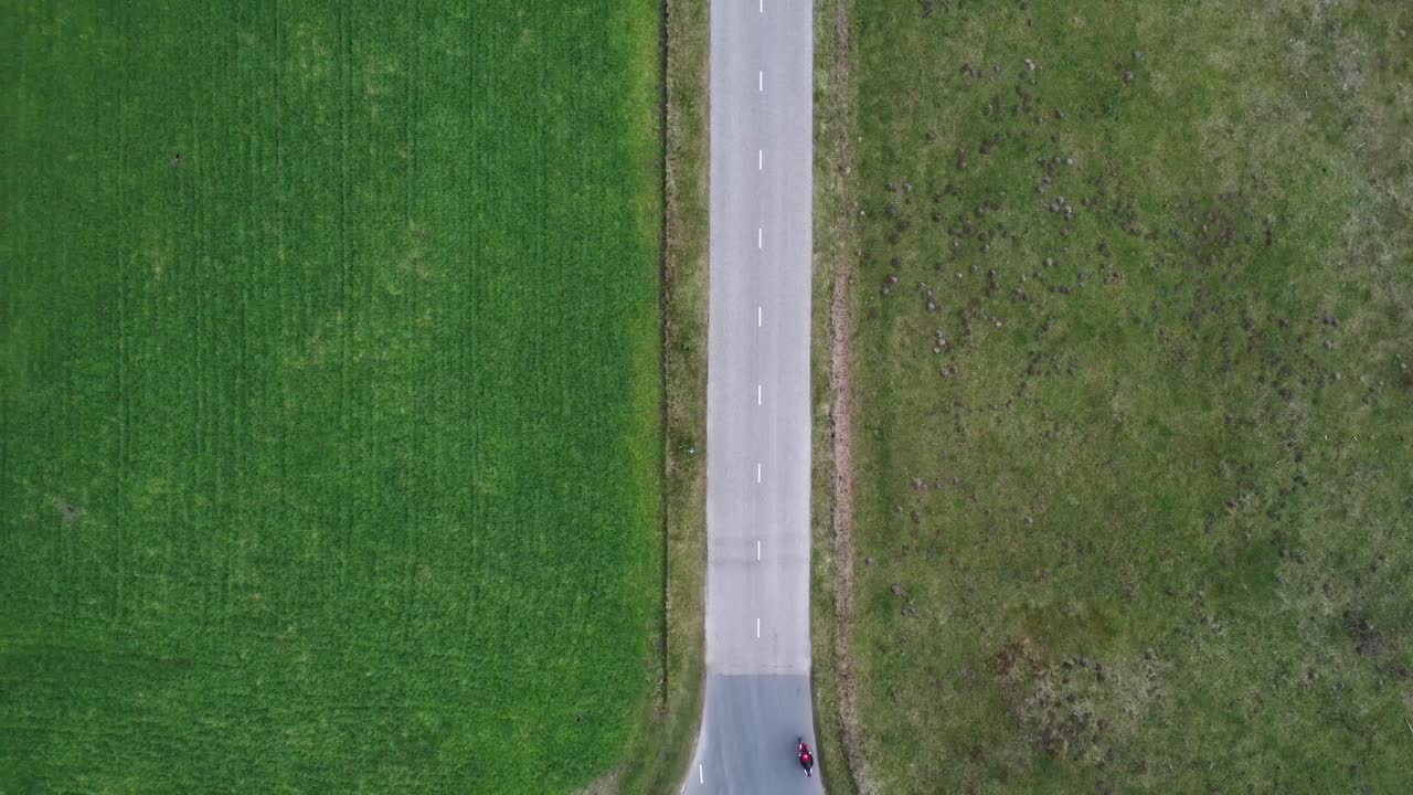 오토바이 운전자가 운전하면서 축소되는 드론 샷