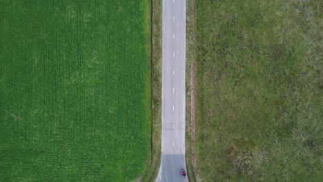 drone shot slowing zooming out with motorcyclist driving by