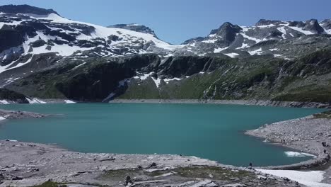 flying towards a beautiful blue lake with snow and ice in the austrian alps, uttendorf weissee