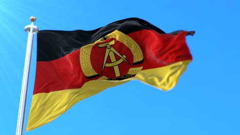 flag of the german democratic republic or east germany waving in blue sky. loop