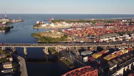 Luftaufnahme-Des-Verkehrs-Auf-Der-Autobahnbrücke-Neben-Dem-Containerhafen-Von-Buenos-Aires-Bei-Sonnenuntergang