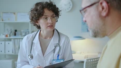 female doctor interviewing patient and taking notes during consultation