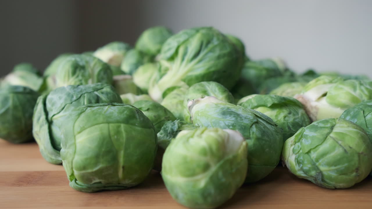 tiro de empuje en cámara lenta hacia un montón de coles de bruselas crudas frescas sobre una mesa de madera