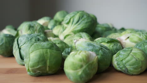 slow motion push-in shot towards heap of fresh raw brussels sprouts on wooden tabletop