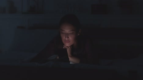 woman using smartphone in bed at night