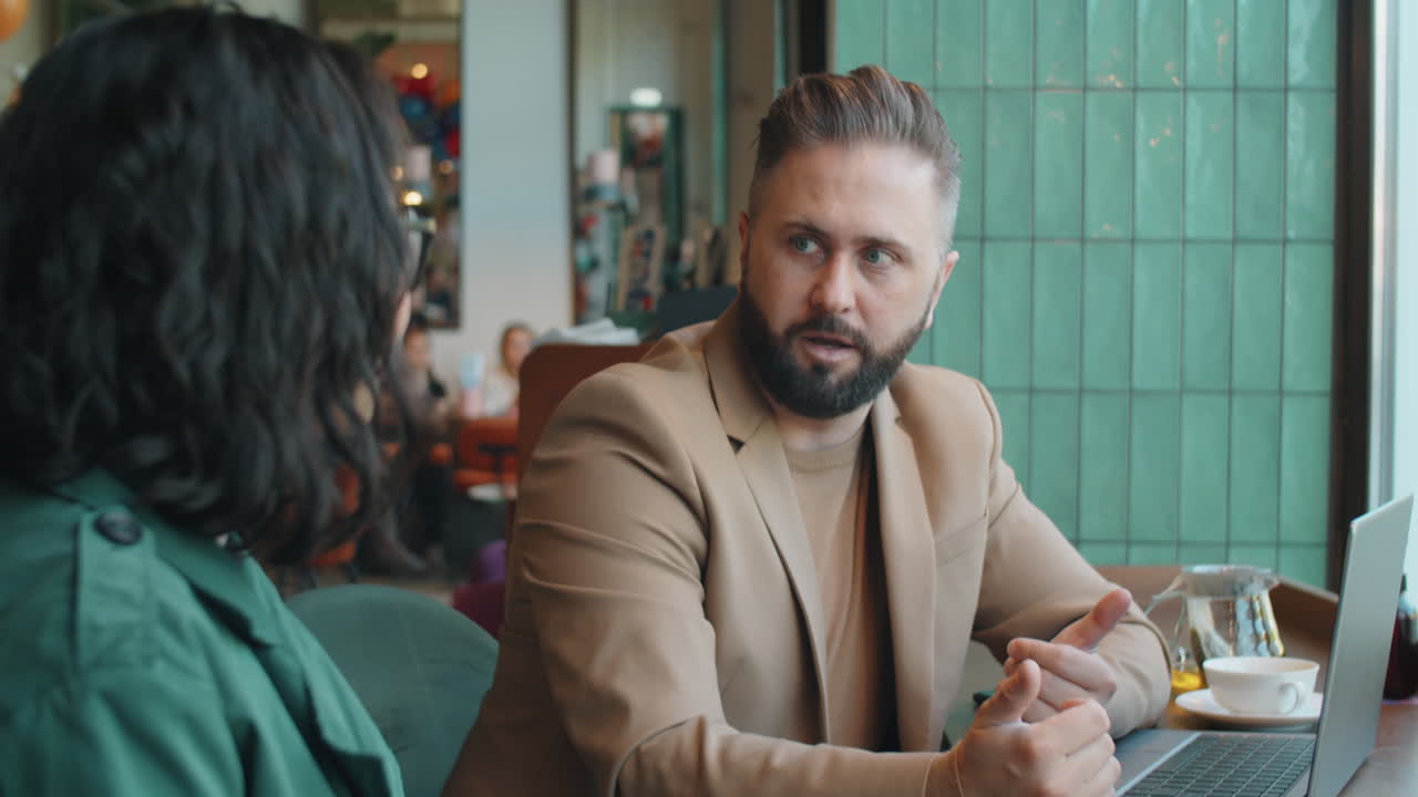 Forretningsmand diskuterer med kvindelig kollega på café
