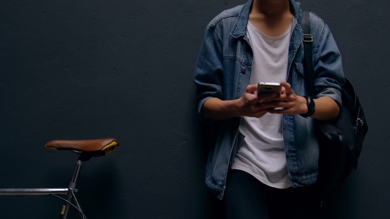 Uomo che usa il cellulare appoggiato al muro 4k