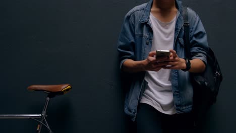 Man-using-mobile-phone-while-leaning-against-wall-4k