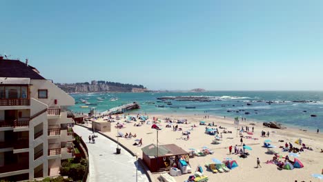 Slow-rising-shot-of-tourists-relaxing-on-the-Pejerrey-beach-in-Algarrobo,-Chile