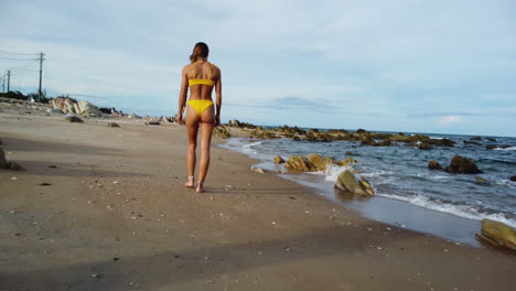 A-gorgeous-lady-walks-along-the-beach,-overlooking-the-sea