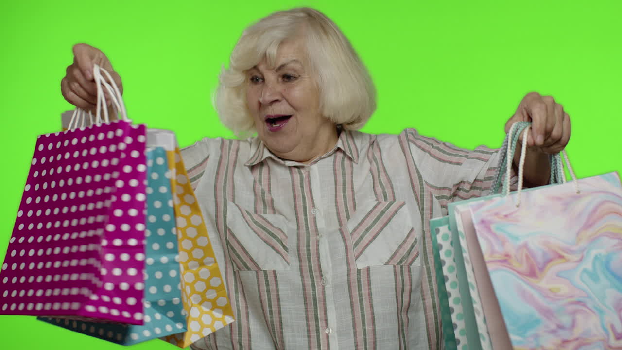 상급 할머니가 쇼핑 가방을 올리고, 축하하고, 구매에 만족하고, 할인합니다.
