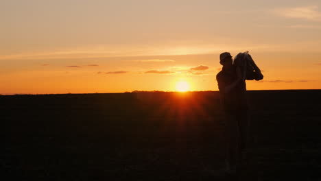 silhouette of a farmer carrying a load at sunset