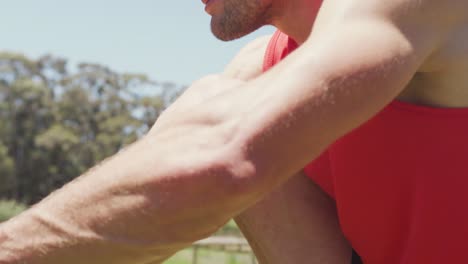 hombre caucásico en forma con ropa deportiva atando zapatos sentado al aire libre al sol preparándose para el ejercicio