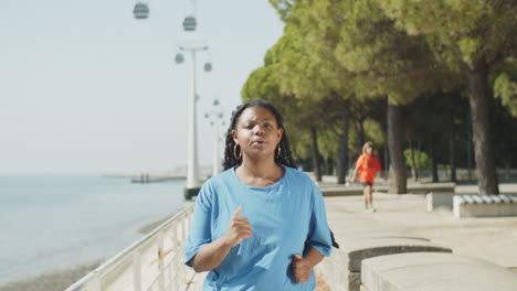 vue frontale d'une femme fatiguée faisant du jogging le long d'une piste de course dans un parc