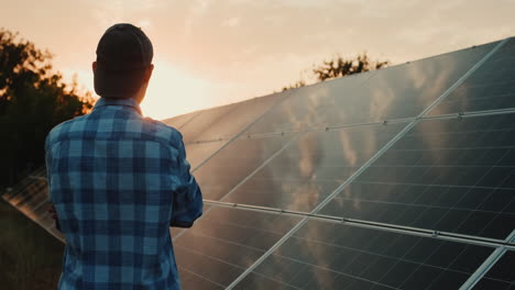 el hombre mira los paneles solares al atardecer