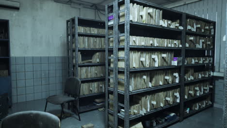 una habitación vacía y polvorienta con estanterías metálicas llenas de libros