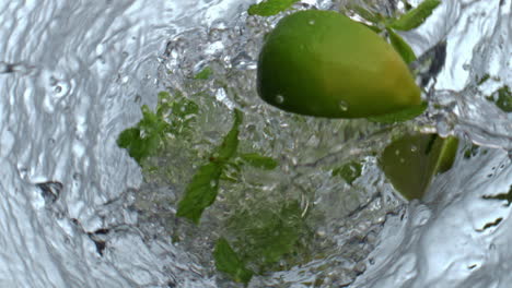 lime mint falling water glass top view. fresh citrus slices throwing in drink