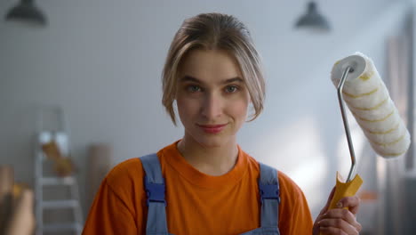 Smiling-woman-looking-camera-in-new-house.-Happy-girl-posing-with-paint-roller.