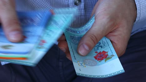 a man in a business shirt counting malaysia money called ringgit. various banknotes