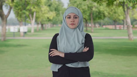 confident muslim woman standing crossed hands in park