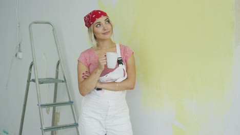 Smiling-woman-painter-standing-with-drink