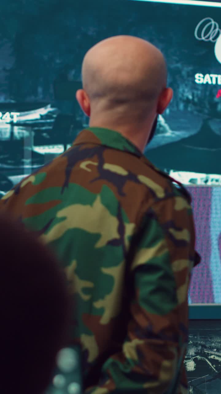 Bald Bearded Man in Military Uniform Observing Screens in Control Room