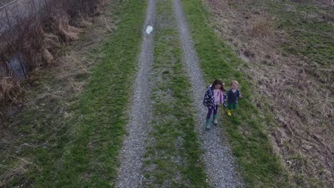two lovely kids holding hands while walking on the stony pathway at the meadow in monroe, michigan - high angle shot