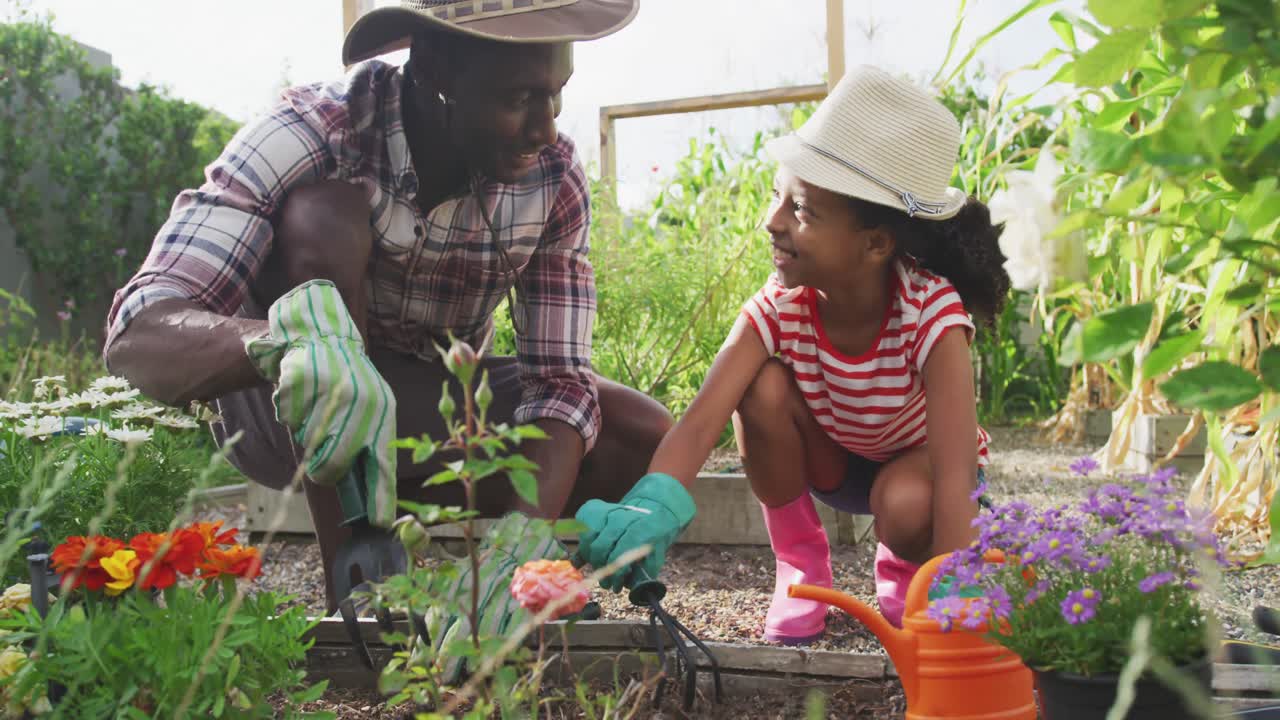 padre y hija afroamericanos haciendo jardinería juntos