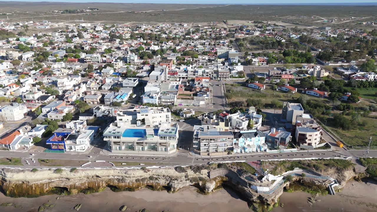 A captivating drone view of Las Grutas, showcasing the coastal residential area with buildings right by the beach.