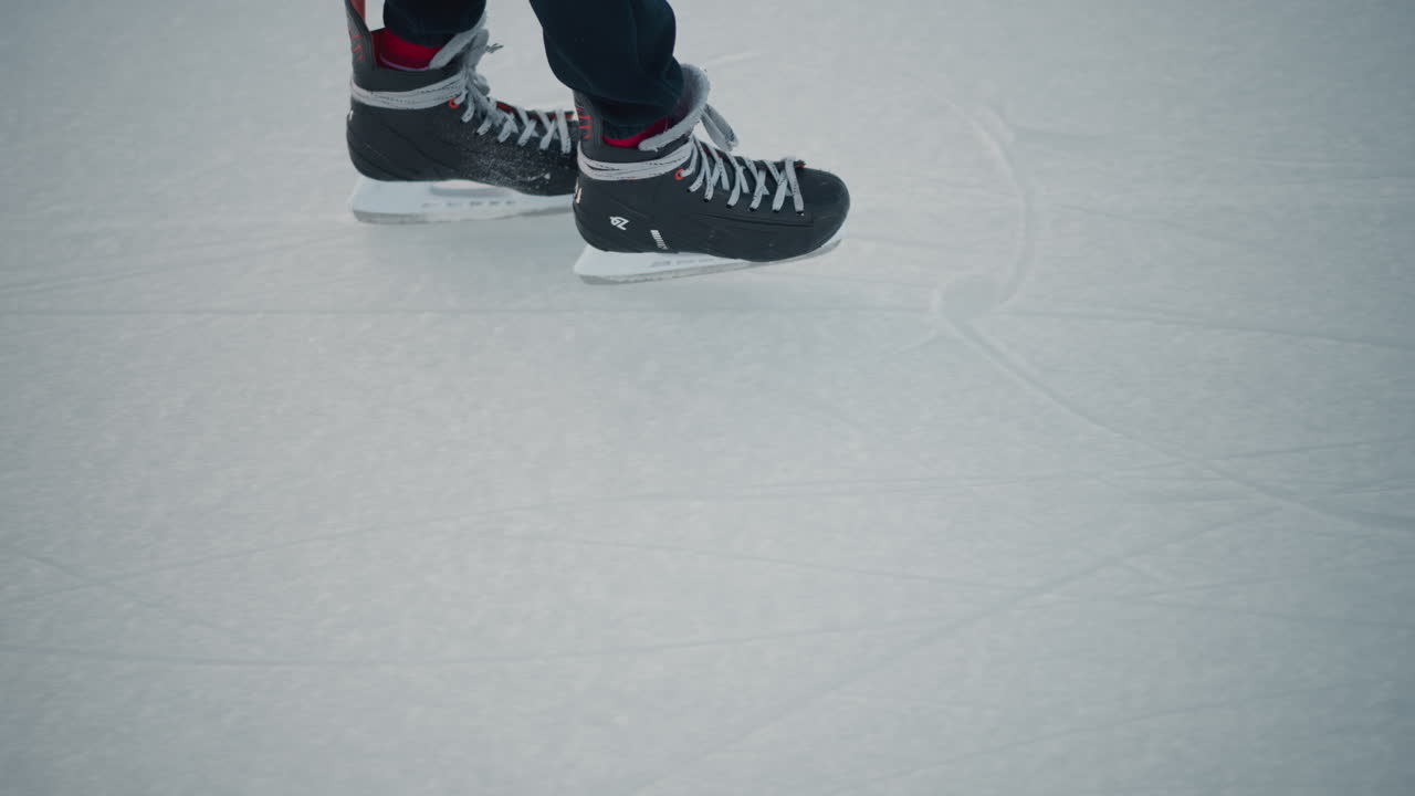 close up ice surface showing skate markings and ringed hand gliding over iced rink winter light illuminating icy texture creating sense of smooth motion and cold sport environment