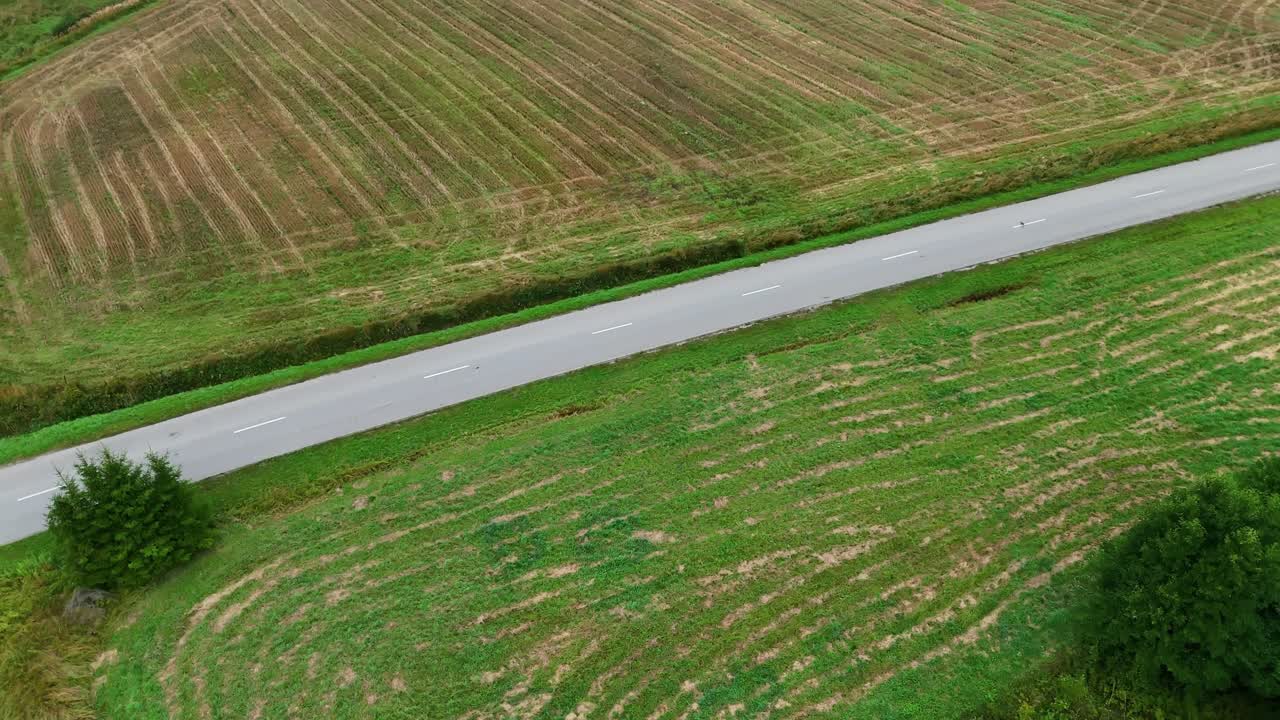 Straight Road Along The Farmland In Daytime In Latvia. - aerial shot