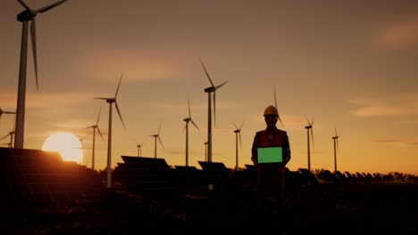 engineer working at a wind and solar farm at sunset