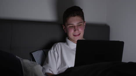 teenage boy sitting on sofa using laptop at home shot on r3d