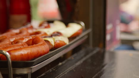un primer plano de los perritos calientes cocinando en el puesto 1 del mercado de comida callejera